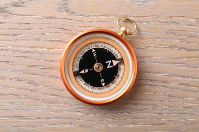 Photo of One compass on wooden table, top view