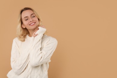 Photo of Happy woman in stylish warm sweater on beige background. Space for text