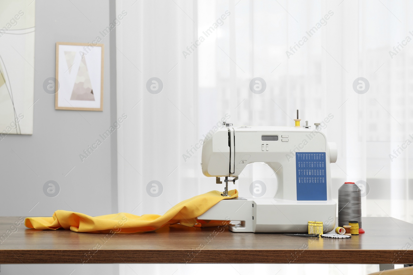 Photo of Sewing machine with fabric and craft accessories on wooden table indoors