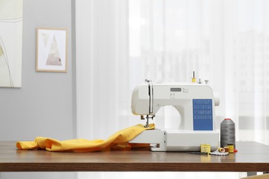 Sewing machine with fabric and craft accessories on wooden table indoors