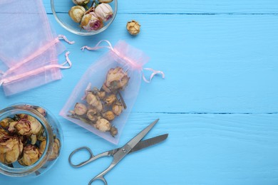 Photo of Scented sachet with dried roses and scissors on light blue wooden table, flat lay. Space for text