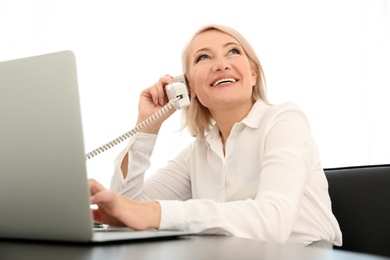 Mature woman talking on phone at workplace