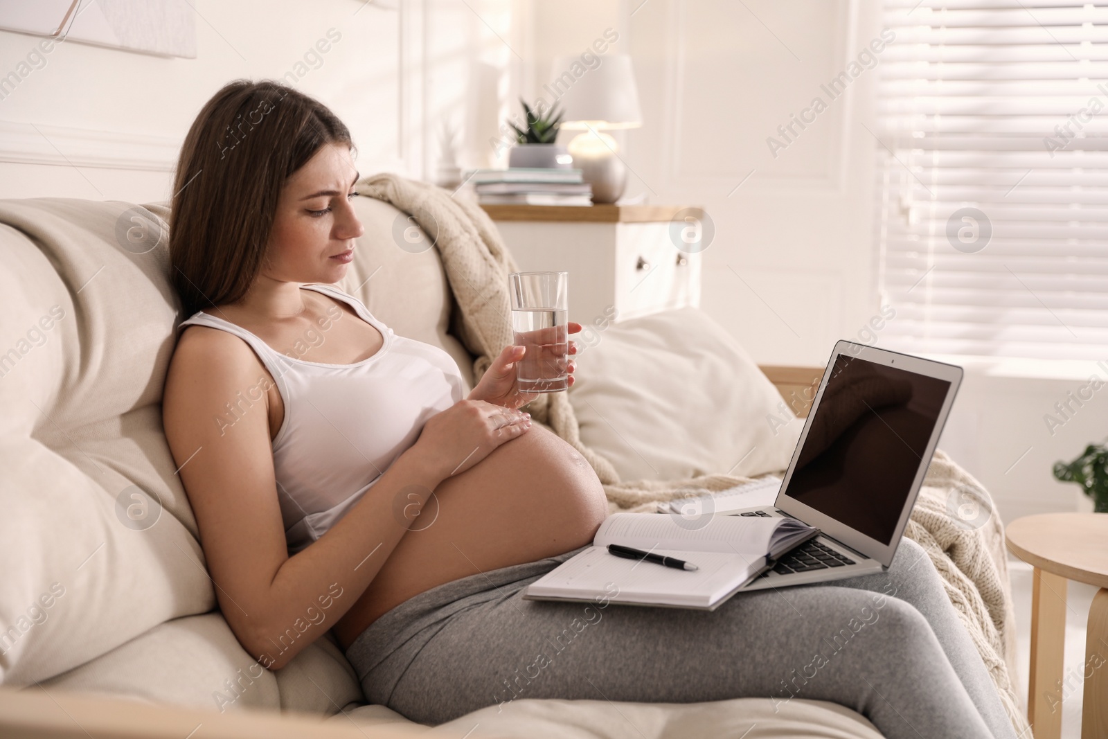 Photo of Tired pregnant woman working on sofa at home. Maternity leave