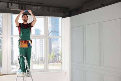 Photo of Electrician repairing ceiling wiring with insulting tape indoors
