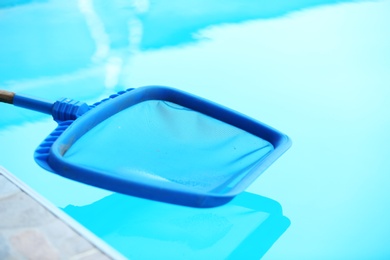 Photo of Cleaning outdoor pool with scoop net, closeup