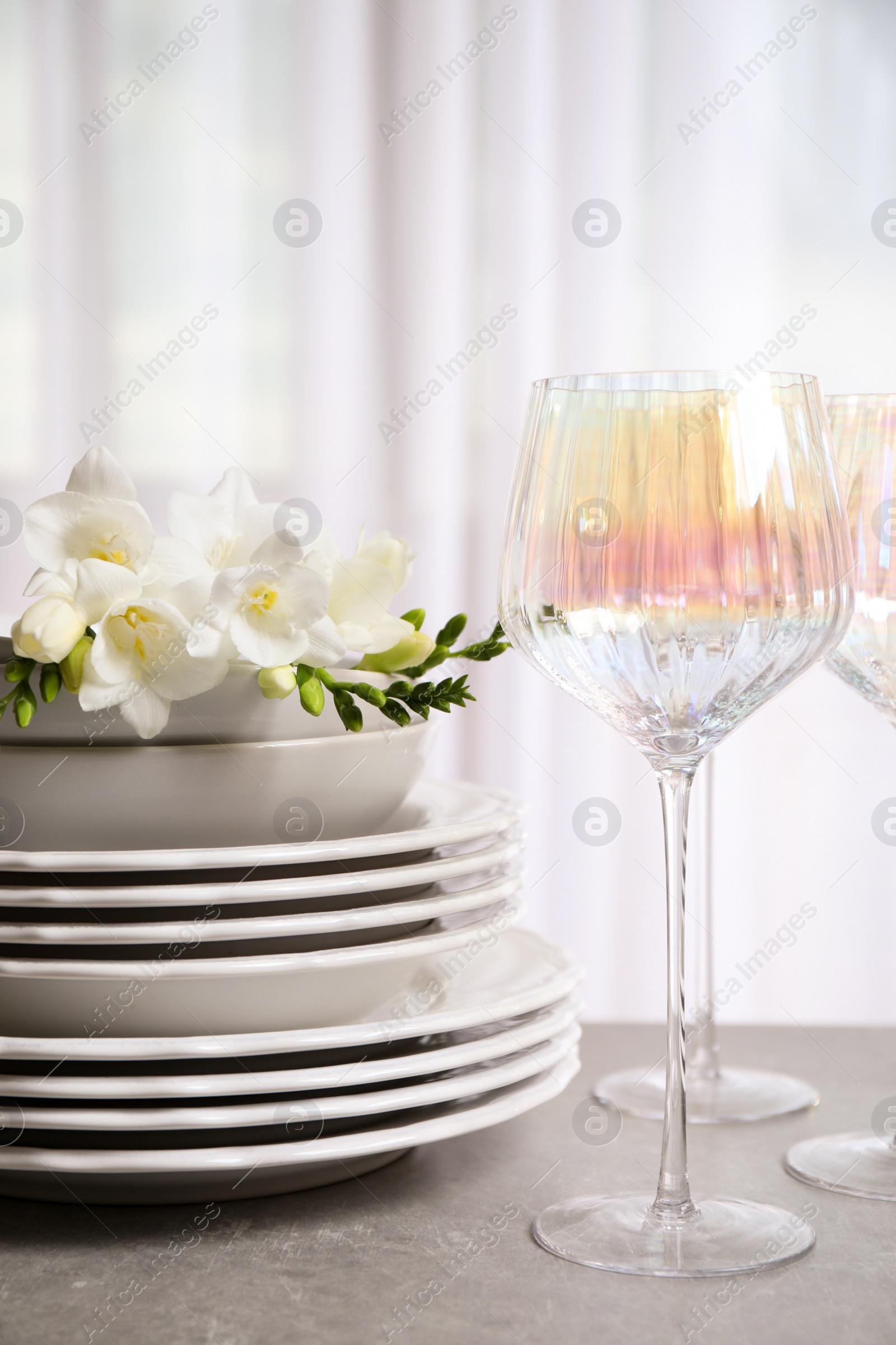 Photo of Set of glasses and dishes with flowers on light grey table