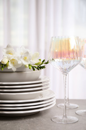 Photo of Set of glasses and dishes with flowers on light grey table