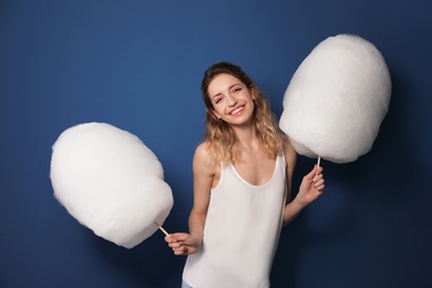 Portrait of pretty young woman with cotton candy on blue background