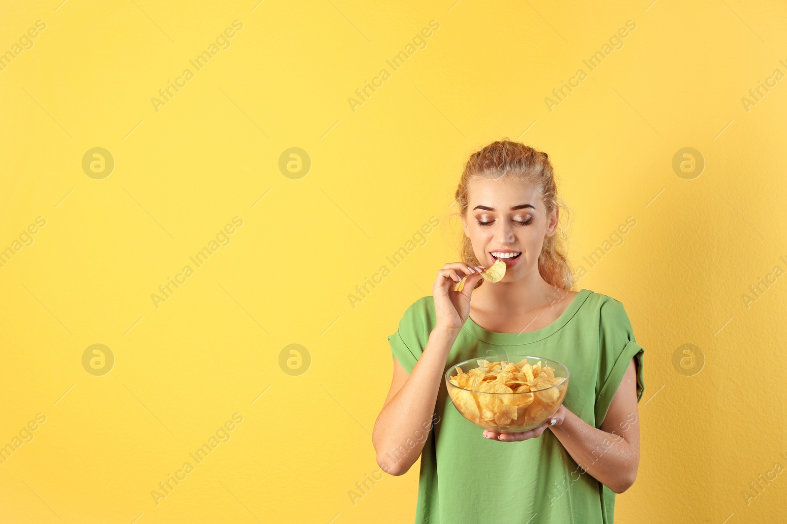 Photo of Woman eating potato chips on color background. Space for text