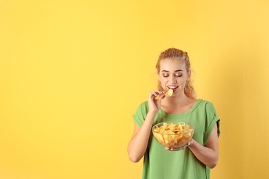 Woman eating potato chips on color background. Space for text