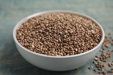 Photo of Bowl with organic hemp seeds on light blue wooden table, closeup