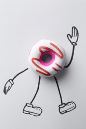 Toy donut with drawn legs and hands on white background, top view