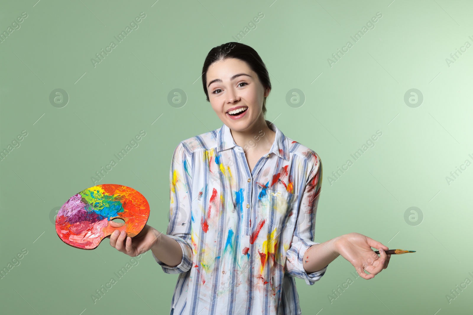 Photo of Woman with painting tools on pale green background. Young artist