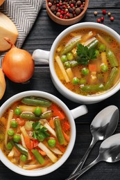 Bowls of tasty turnip soup and ingredients on dark wooden table, flat lay