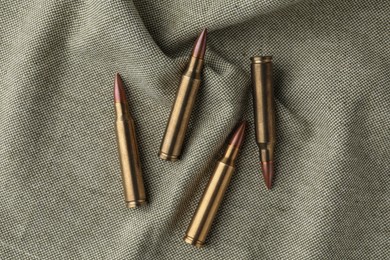 Photo of Many brass bullets on burlap, flat lay