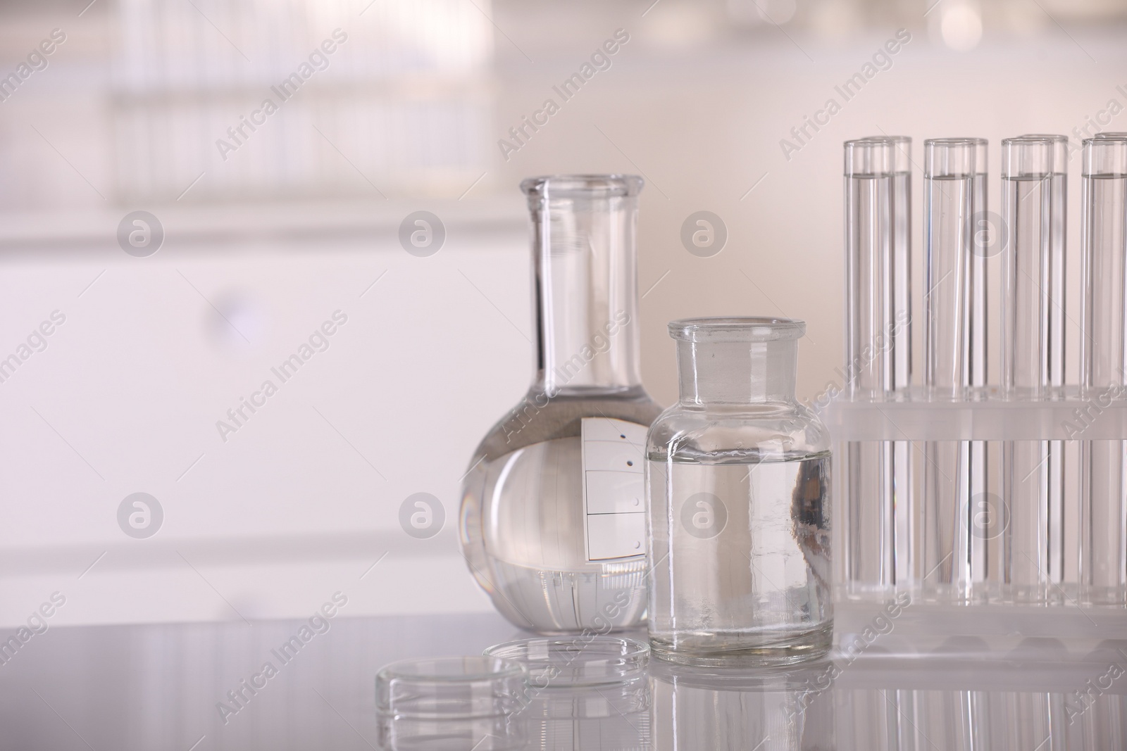 Photo of Laboratory analysis. Different glassware with liquid on white table indoors, space for text