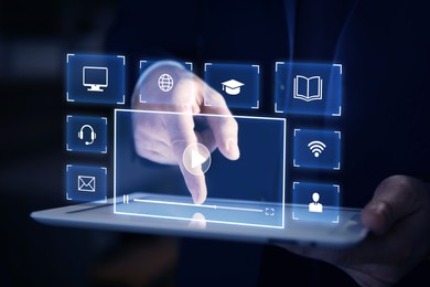 Image of Webinar. Man using tablet on dark background, closeup. Virtual screen with icons over device