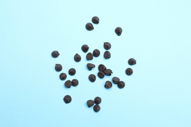 Delicious dark chocolate chips on light blue background, top view