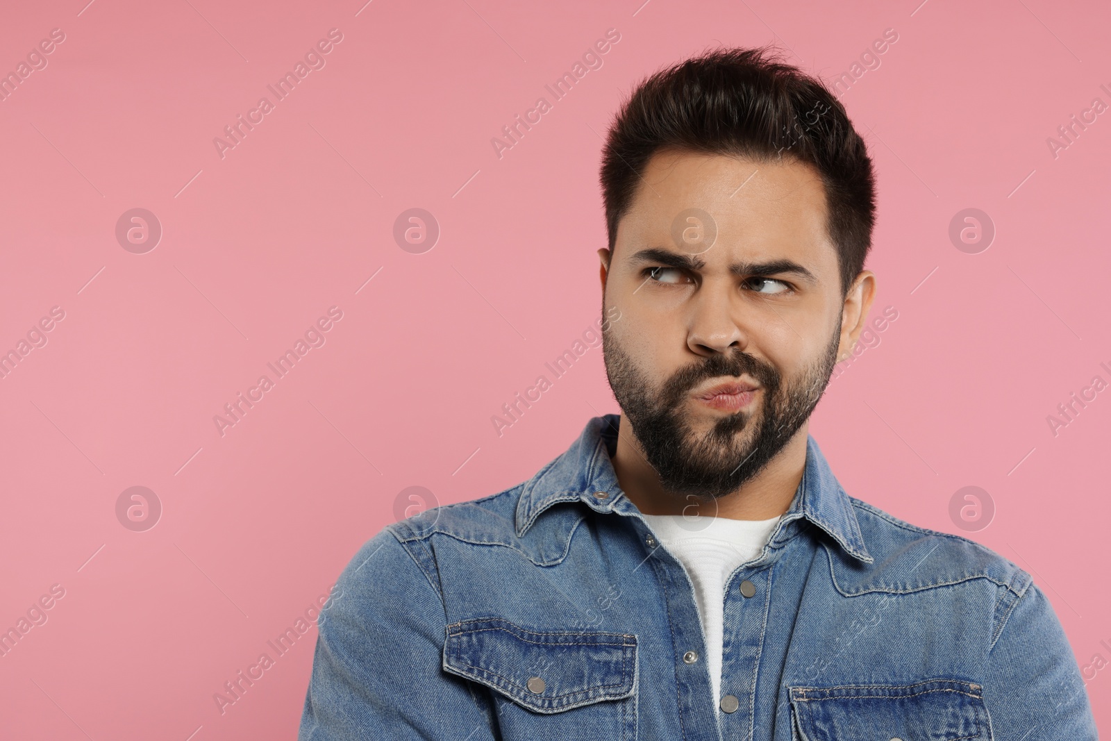 Photo of Resentful man on pink background. Space for text