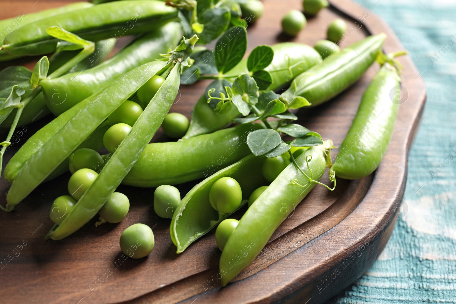 Photo of Wooden board with green peas on table, closeup