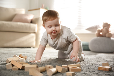 Photo of Cute baby playing with wooden blocks at home