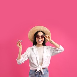 Photo of Happy female tourist with toy plane on pink background