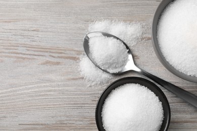 Granulated sugar on light wooden table, flat lay. Space for text