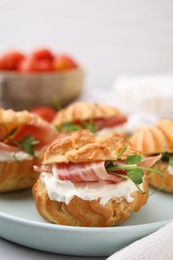 Photo of Delicious profiteroles with cream cheese and prosciutto on plate, closeup