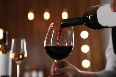 Photo of Waitress pouring wine into glass in restaurant, closeup