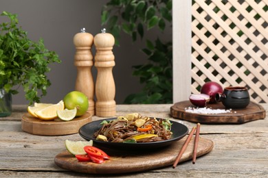 Photo of Stir-fry. Tasty noodles with meat and vegetables served on wooden table