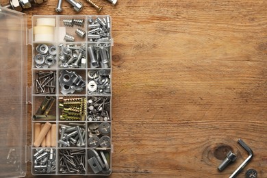 Photo of Organizer with many different fasteners on wooden table, flat lay. Space for text
