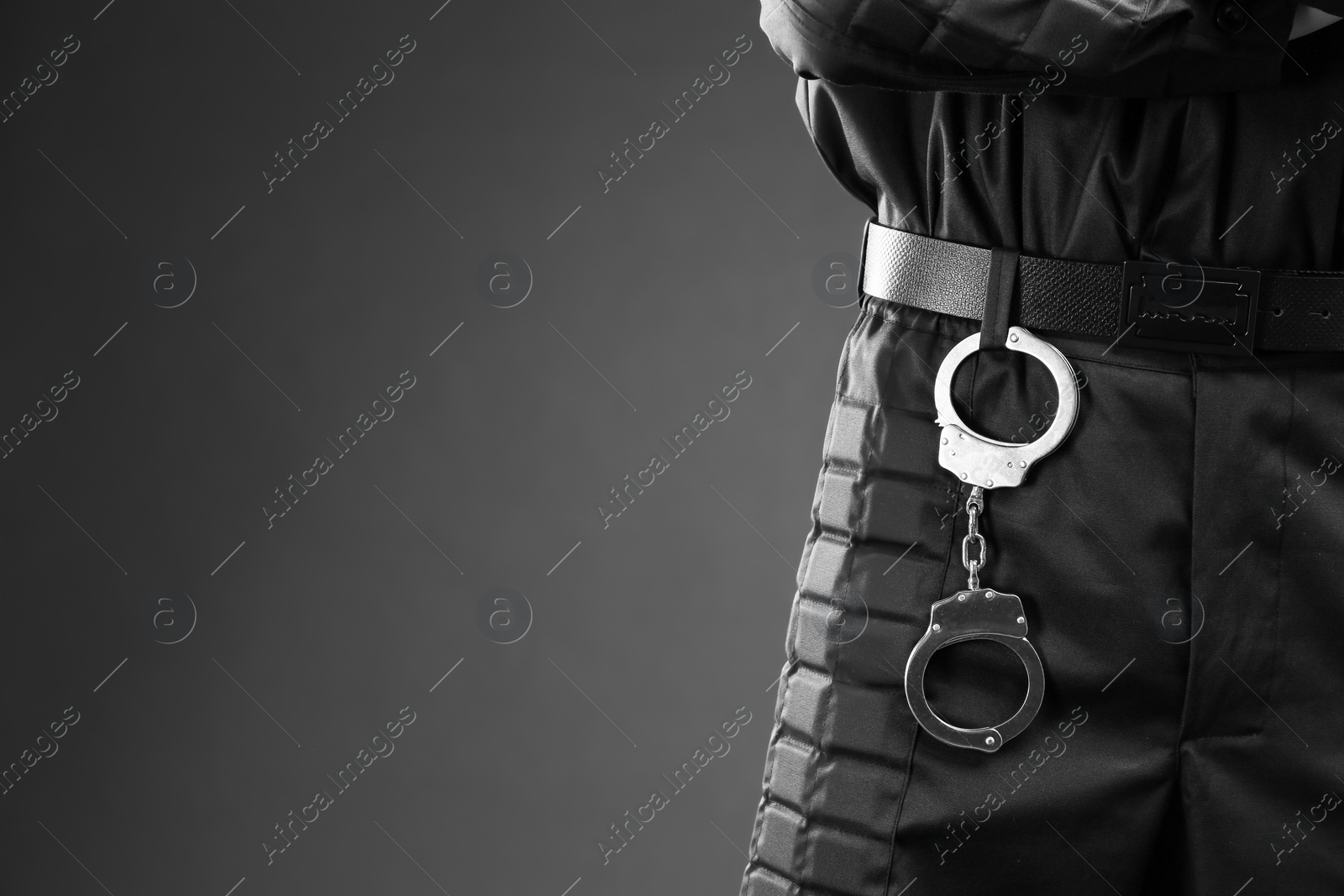 Photo of Male security guard with handcuffs on dark background, closeup