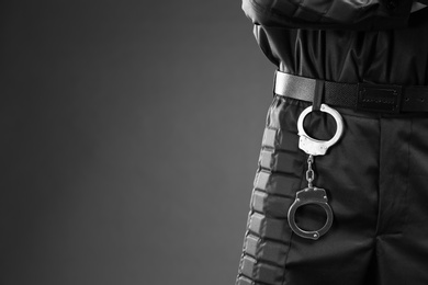 Photo of Male security guard with handcuffs on dark background, closeup