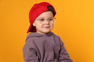 Photo of Cute little boy in glasses on orange background