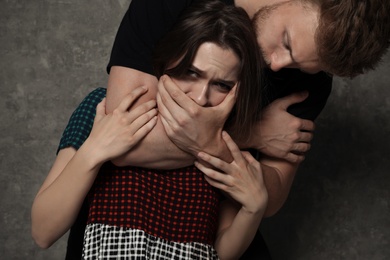 Photo of Man abusing young woman on grey background. Stop sexual assault