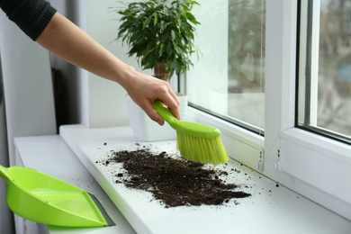 Woman cleaning window sill from soil at home, closeup