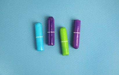 Photo of Four tampons on turquoise background, flat lay