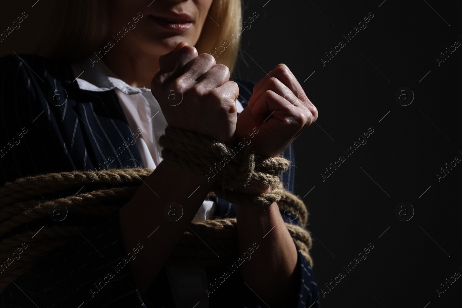 Photo of Woman tied up and taken hostage on dark background, closeup. Space for text