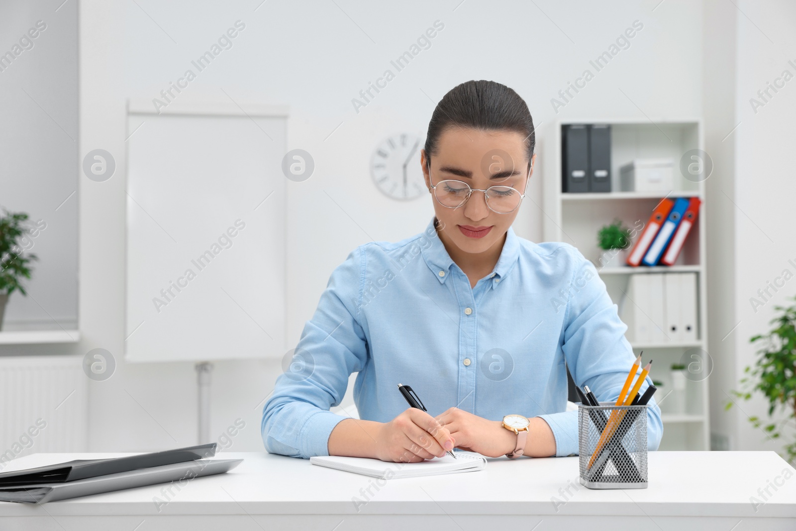 Photo of Young female intern working at table in office