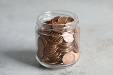 Photo of Glass jar with coins on light grey table, closeup