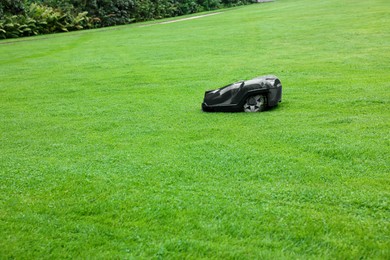 Photo of Modern lawn mower on green grass outdoors. Space for text