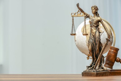 Photo of Figure of Lady Justice with gavel and globe on table, space for text. Symbol of fair treatment under law