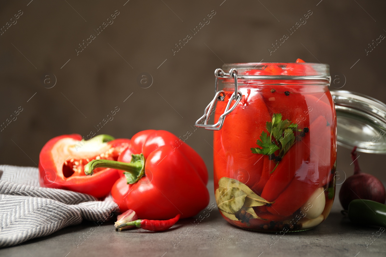 Photo of Glass jar with pickled peppers on grey table