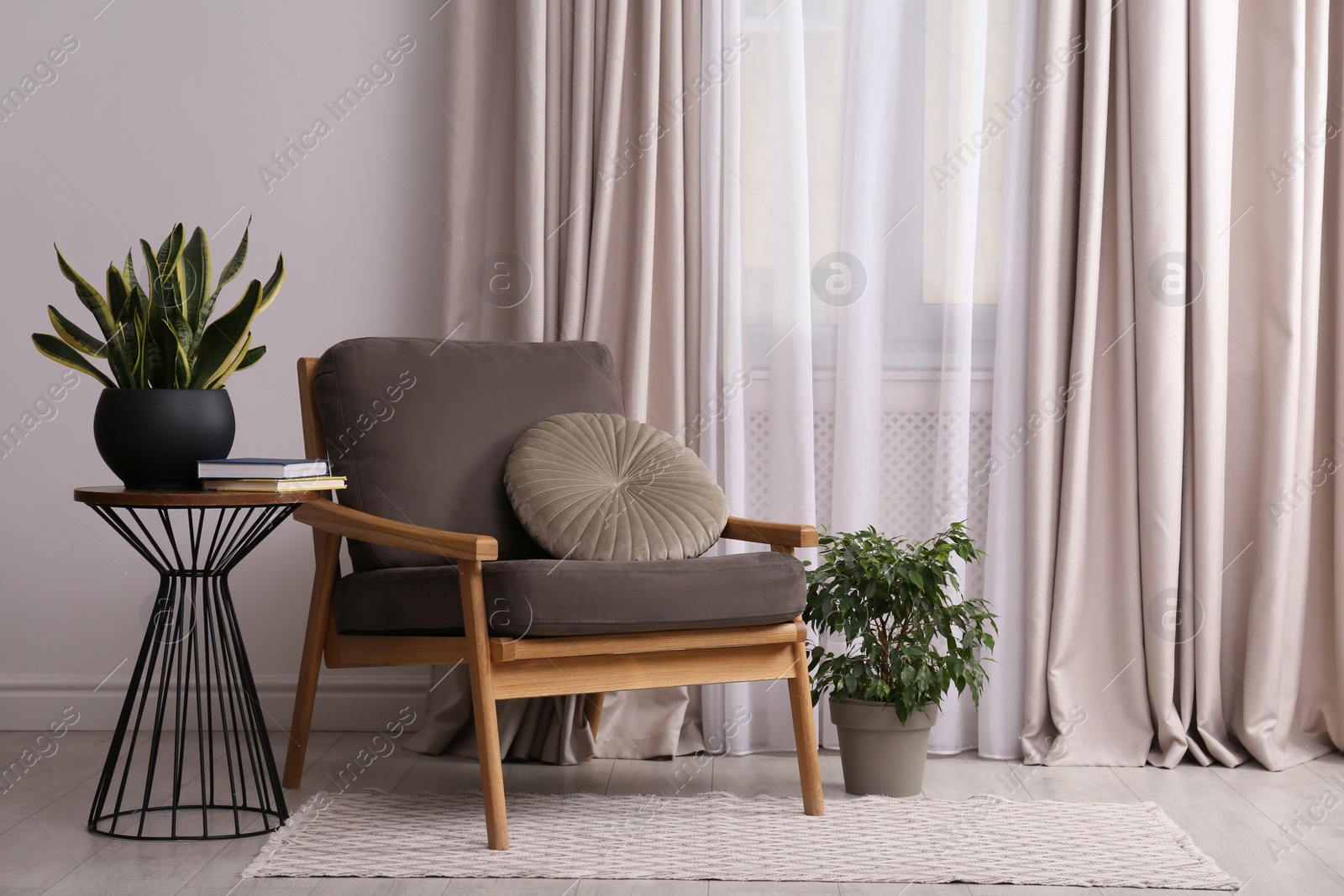 Photo of Comfortable armchair and plants near window in living room. Interior design