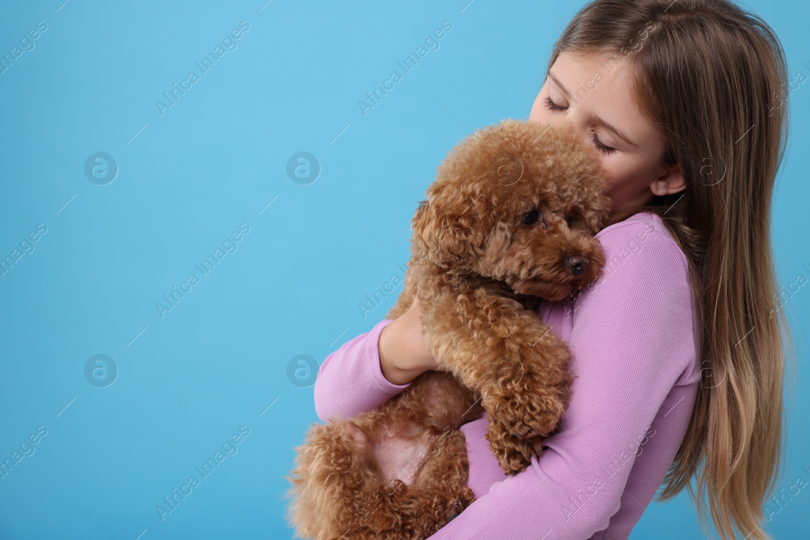 Photo of Little child with cute puppy on light blue background, space for text. Lovely pet