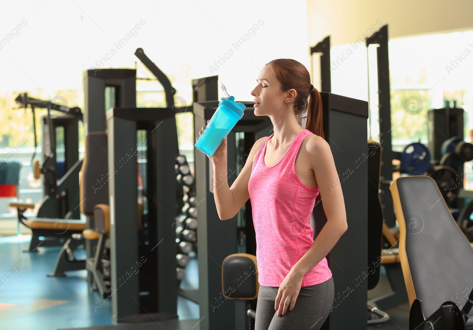 Photo of Athletic young woman drinking protein shake in gym