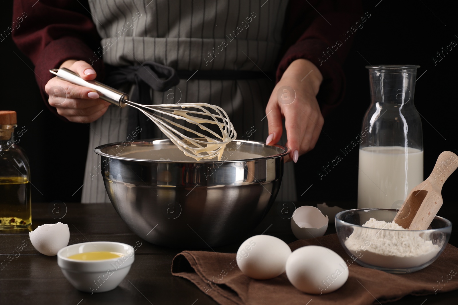 Photo of Woman making dough with whisk in bowl at table, closeup