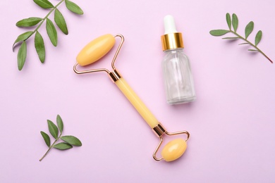 Natural face roller, cosmetic product and leaves on pink background, flat lay
