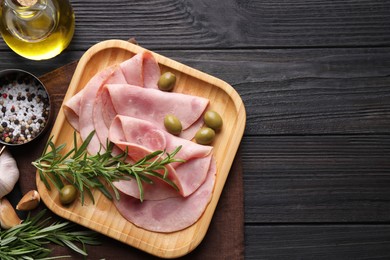 Photo of Slices of delicious ham with rosemary and olives served on dark wooden table, flat lay. Space for text