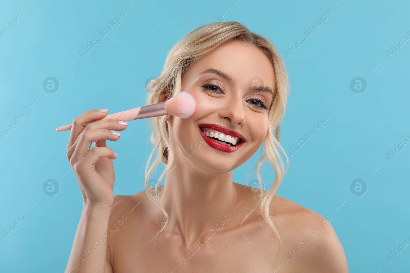 Photo of Beautiful makeup. Smiling woman with brush on light blue background
